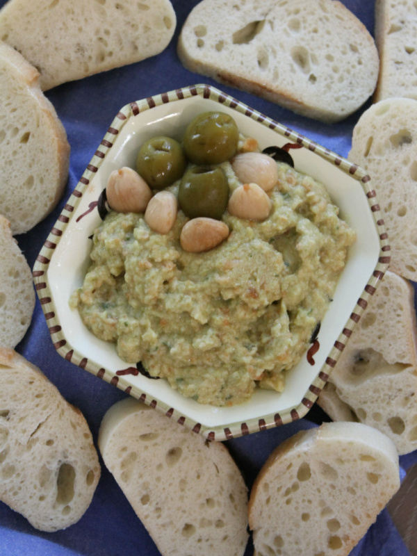 overhead shot of dish of green olive spread surrounded by baguette slices