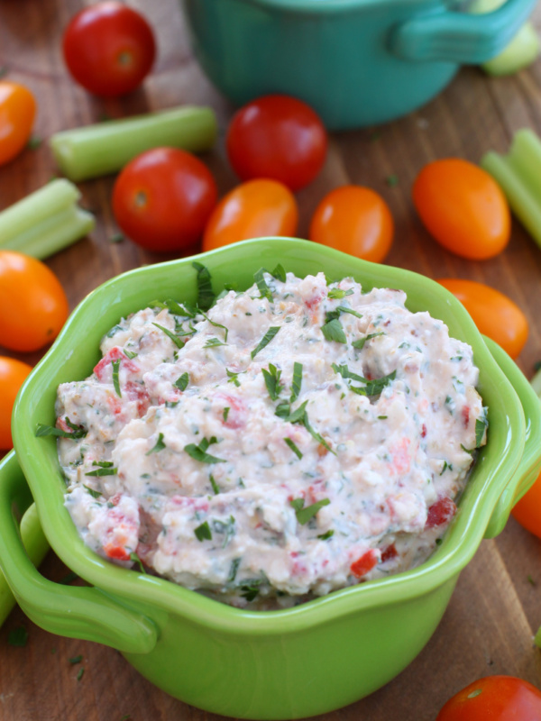 pine nut and feta cheese dip in a green dish surrounded by veggies