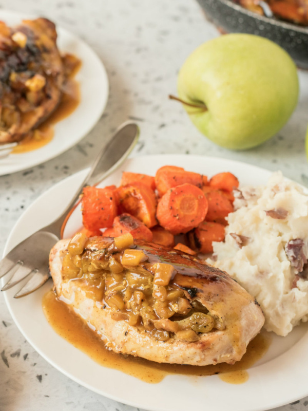 chicken breasts with curried apple stuffing on a plate with potatoes and carrots