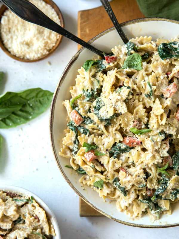 bowl of farfalle pasta with spinach and ricotta cheese with a side of parmesan cheese