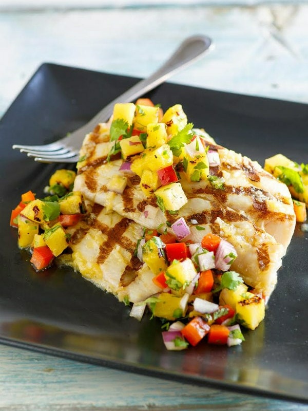 Grilled Mahi Mahi topped with Grilled Pineapple Salsa on a black plate