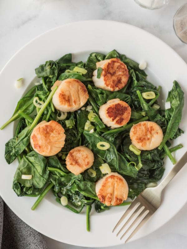 seared jumbo scallops on spinach on plate