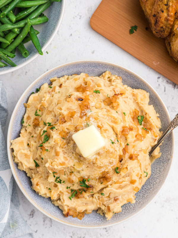 caramelized onion and horseradish mashed potatoes in a bowl with a pat of butter