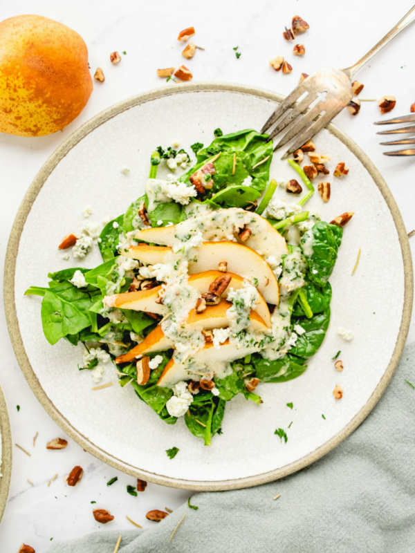 spinach and pear salad on white plate with fork