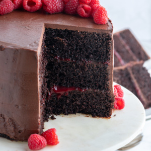 double chocolate cake with raspberry filling on cake stand with slice taken out