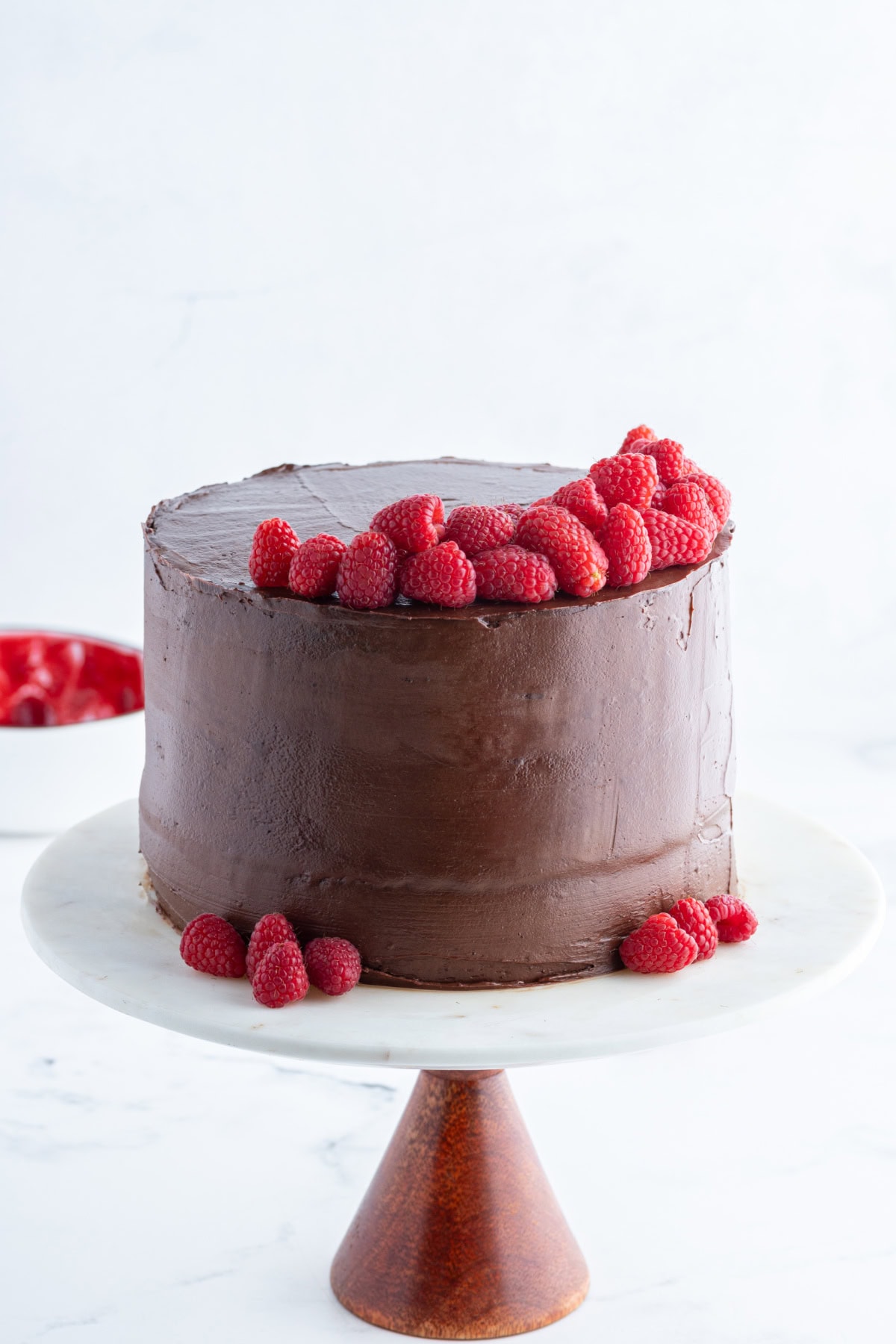 double chocolate cake on cake stand with fresh raspberries on top