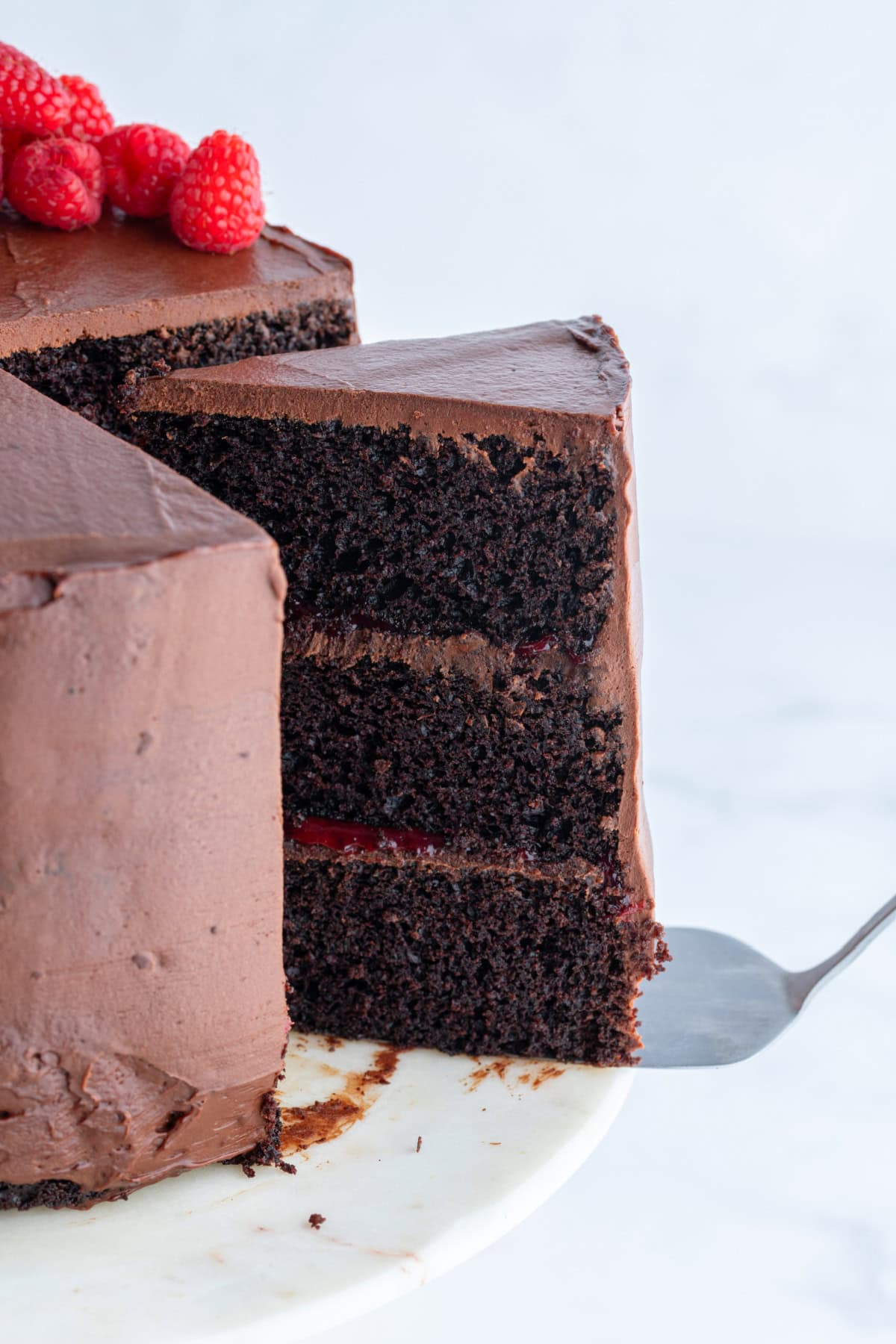 spatula taking out slice of double chocolate cake with raspberry filling