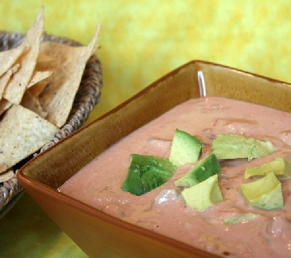 spicy hummus avocado dip in a bowl with chips