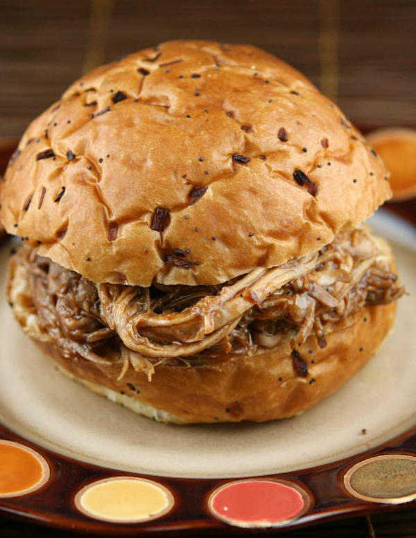 root beer pulled pork sandwich sitting on a brown and white plate with orange and yellow polka dots