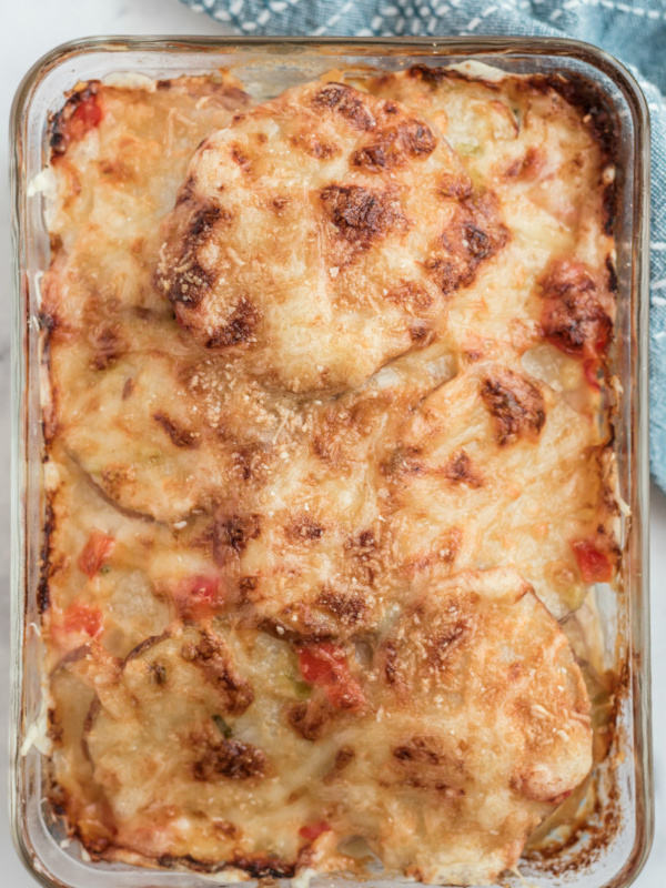 scalloped potatoes with peppers and swiss cheese in baking dish