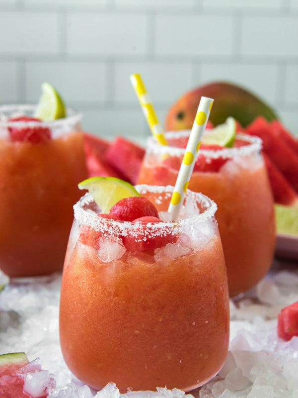 watermelon mango margaritas with yellow straws and lime garnishes