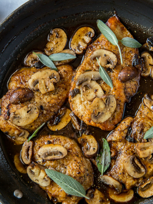 chicken marsala garnished with fresh sage in a skillet