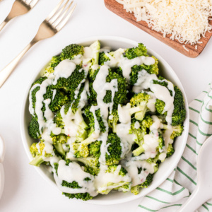 overhead shot of bowl of broccoli with two cheese sauce drizzled on top