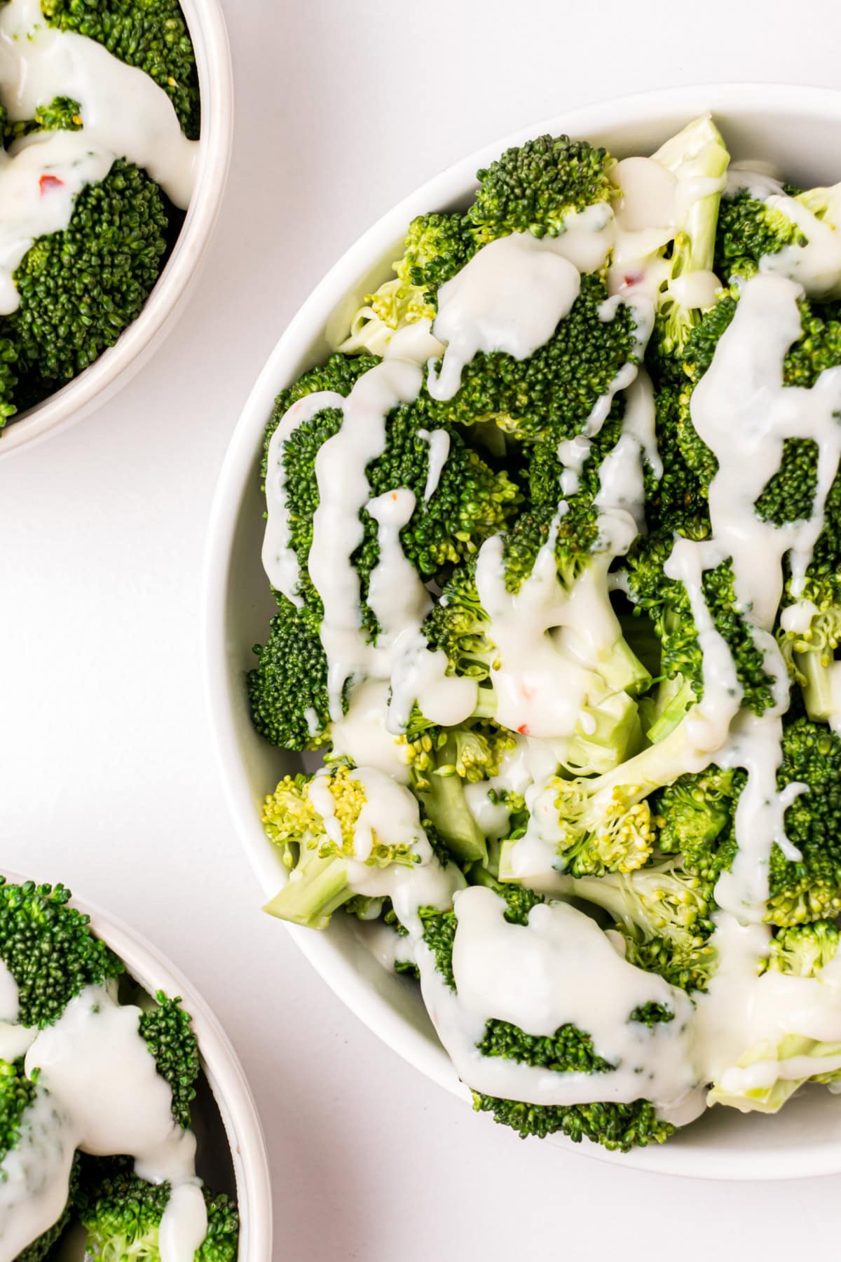 shot of half bowl of broccoli with two cheese sauce drizzled on top