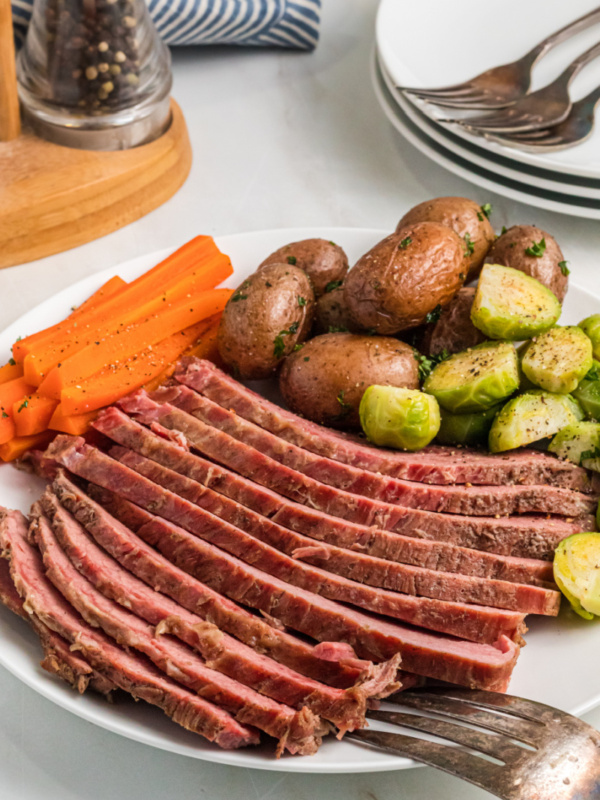 sliced corned beef on a plate with veggies