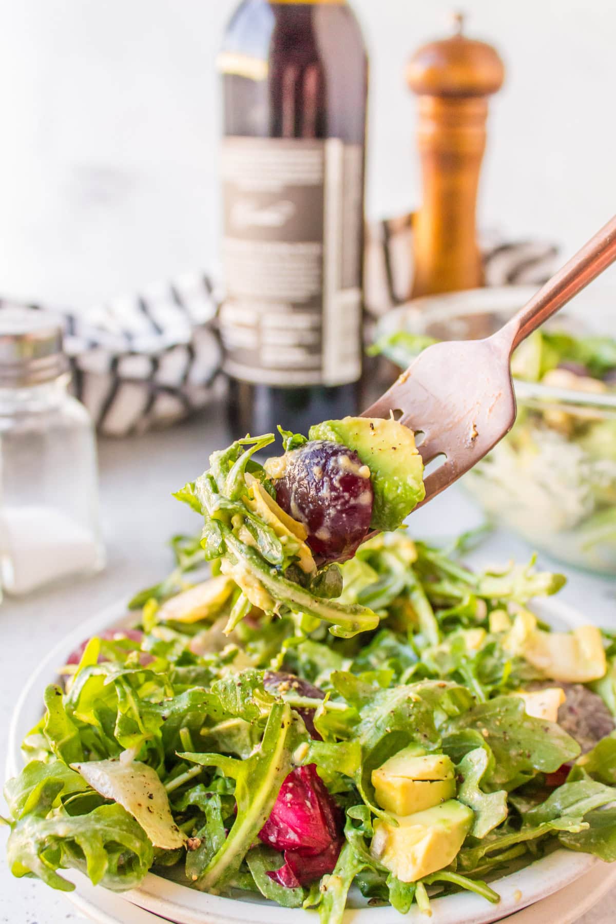 grape avocado and arugula salad with fork full of salad