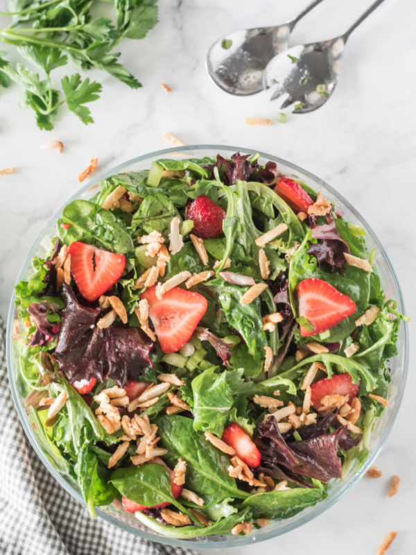 bowl of green salad with strawberries and sugared almonds