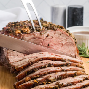 slicing leg of lamb with garlic and rosemary