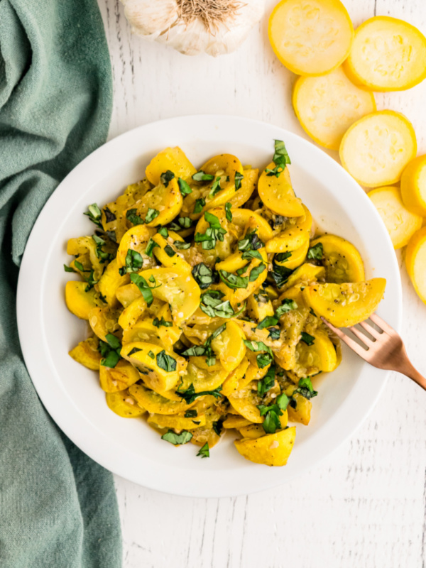 smothered yellow squash and basil in a white dish