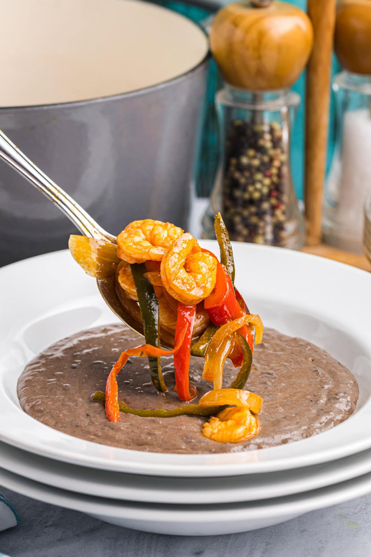 spooning rock shrimp escabeche into bowl of black bean bisque