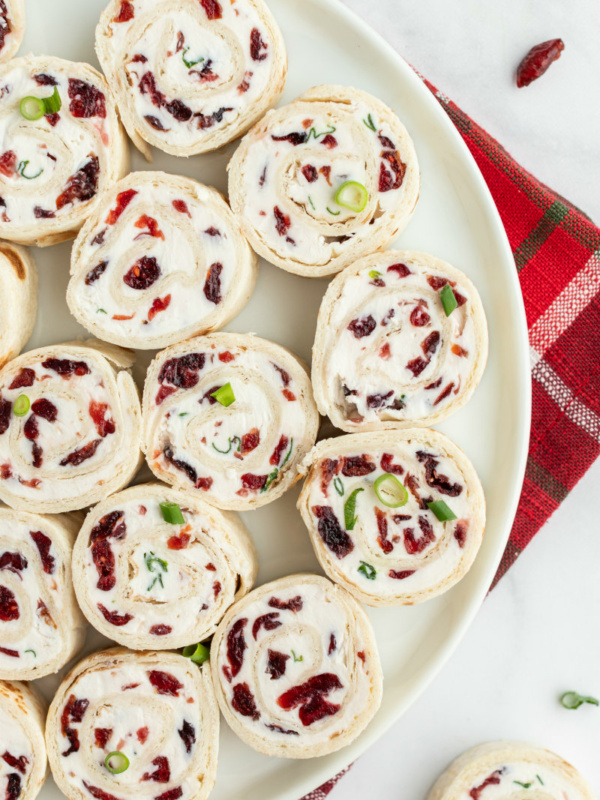 cranberry feta pinwheels on a white platter set on red plaid napkin