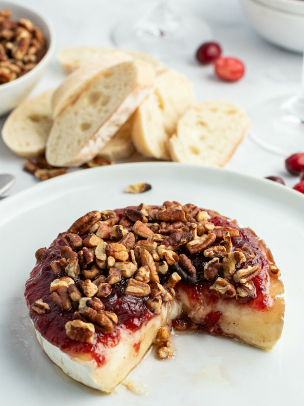 cranberry baked brie displayed with a wedge taken out of it