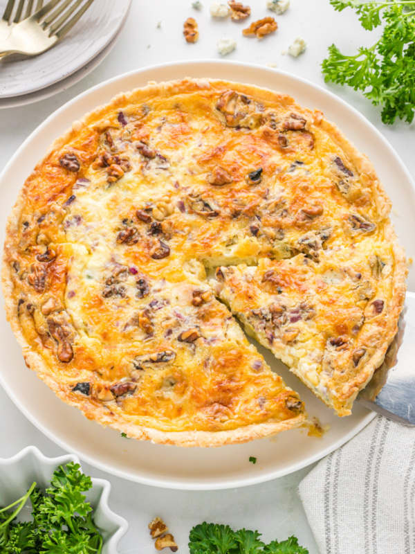 spatula taking out a slice of blue cheese and walnut quiche