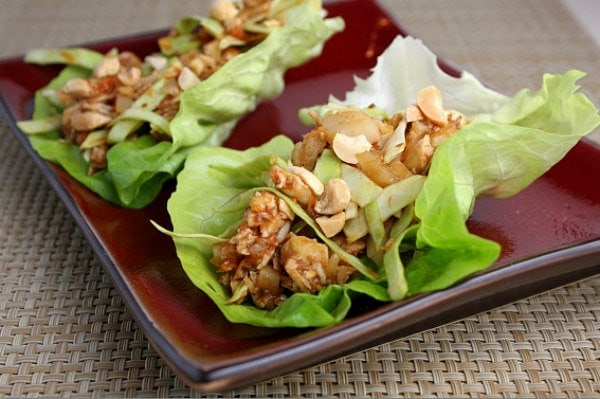 two sweet and spicy lettuce wraps on a burgundy plate