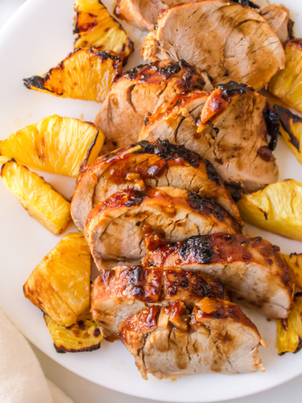 sliced pork tenderloin on a plate with pineapple