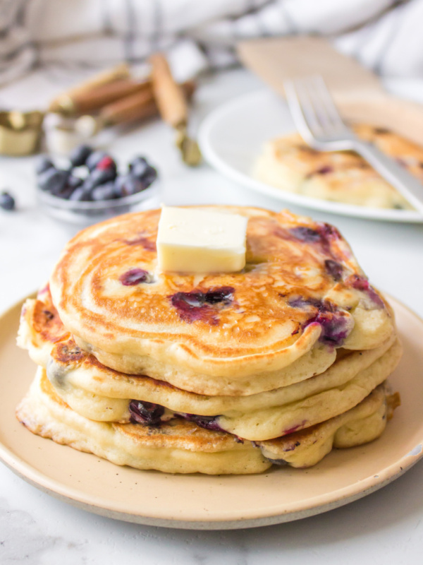 stack of blueberry pancakes with pat of butter on top