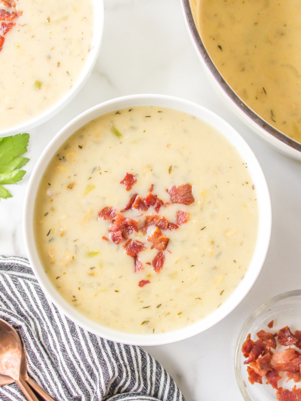 low fat clam chowder in a white bowl topped with bacon