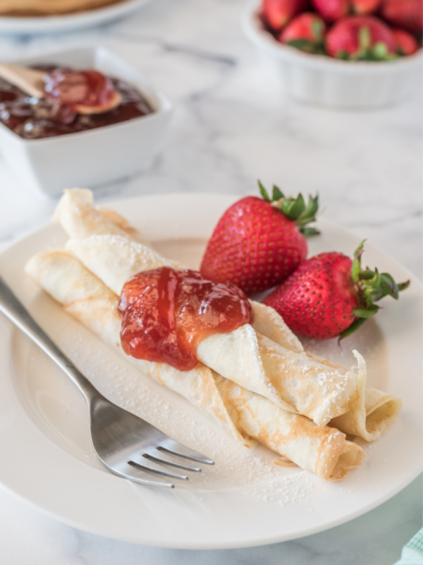 norwegian pancakes topped with strawberry jam with fresh strawberries