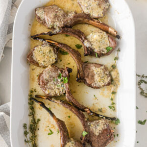 broiled lamb chops on a platter topped with lemon butter sauce