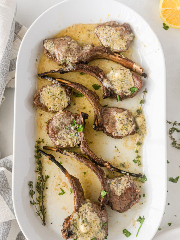 broiled lamb chops on a platter topped with lemon butter sauce