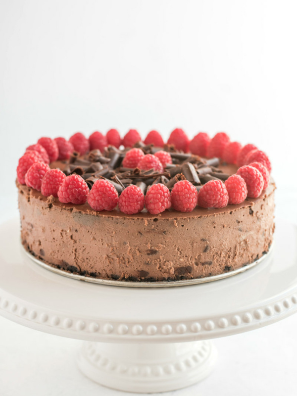 chocolate chocolate chip cheesecake with raspberry garnish on white platter