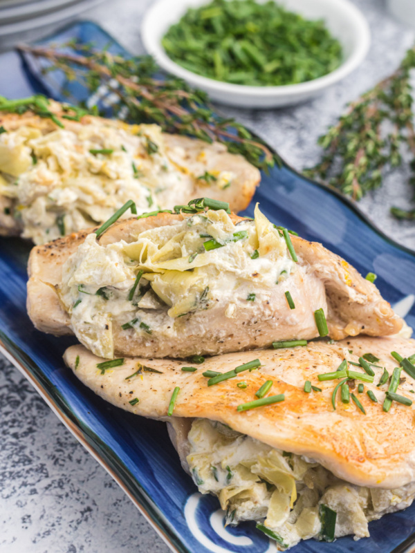 Artichoke and goat cheese stuffed chicken on platter