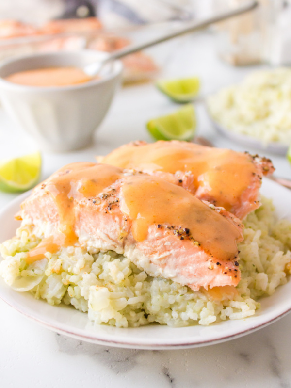 baked salmon on top of rice on a plate with coconut ginger sauce on top