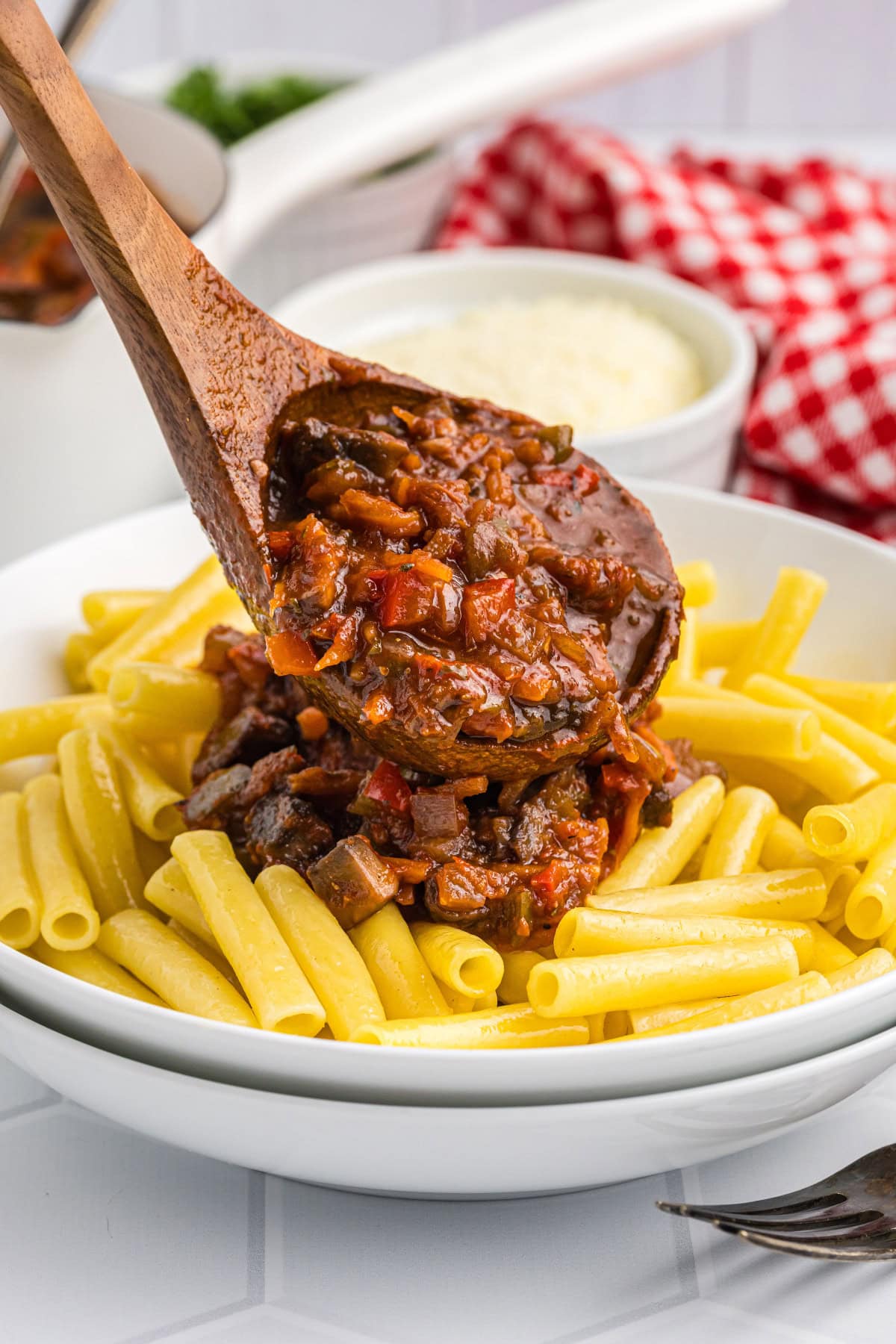 spooning bolognese sauce onto pasta