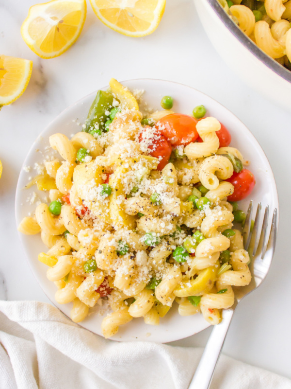 pasta with spring vegetables topped with Parmesan on a plate