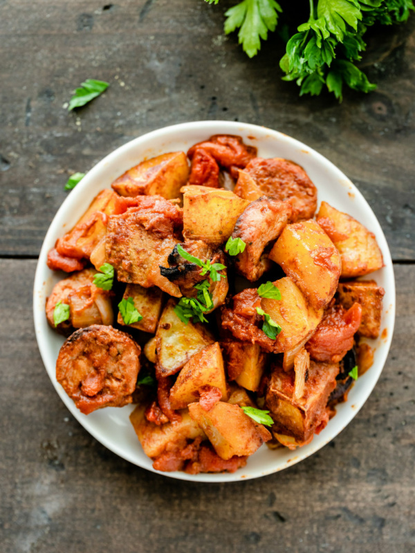 overhead shot of white bowl of portuguese roasted potatoes garnished with fresh parsley