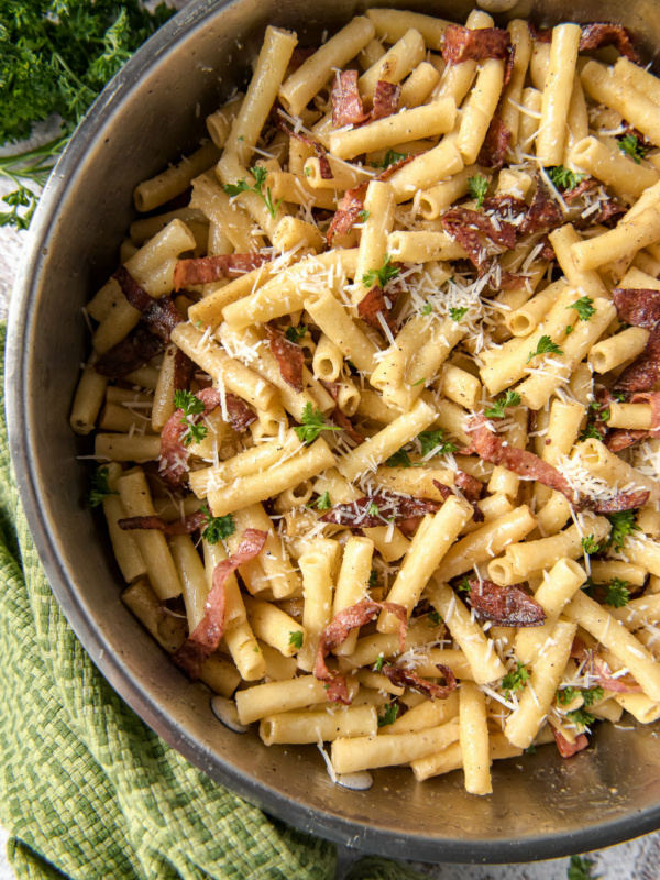 ziti carbonara in a skillet - green cloth napkin and fresh parsley on the side