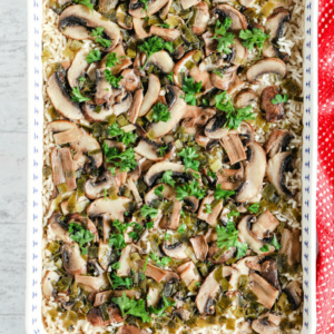 overhead shot of baked mushroom rice in a blue and white casserole dish with a red cloth napkin on the side