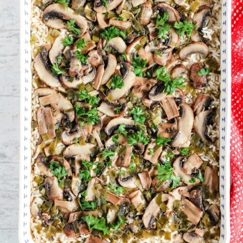 overhead shot of baked mushroom rice in a blue and white casserole dish with a red cloth napkin on the side