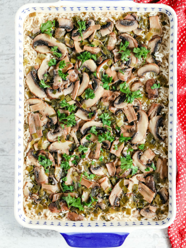 overhead shot of baked mushroom rice in a blue and white casserole dish with a red cloth napkin on the side