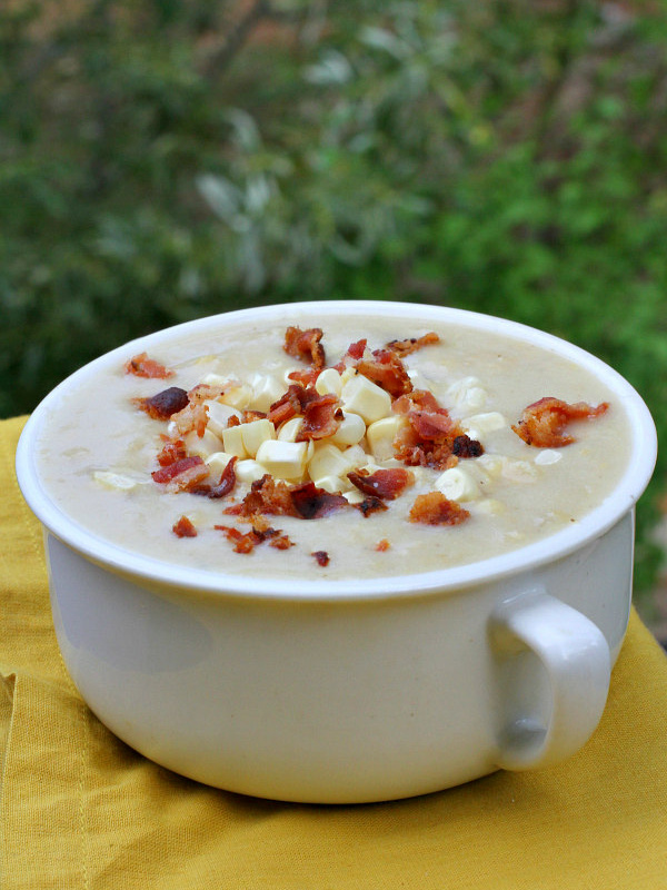 white bowl of fresh corn chowder with bacon on top set on a yellow napkin