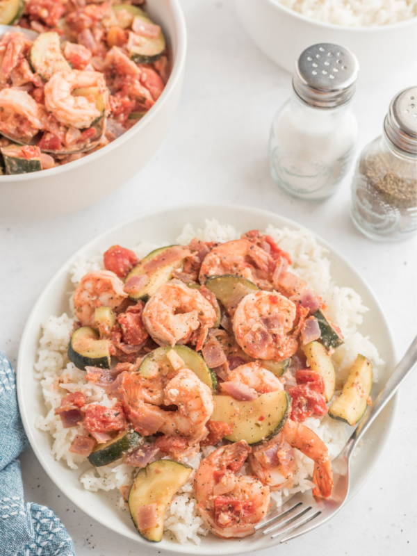 greek style shrimp over rice on a white plate