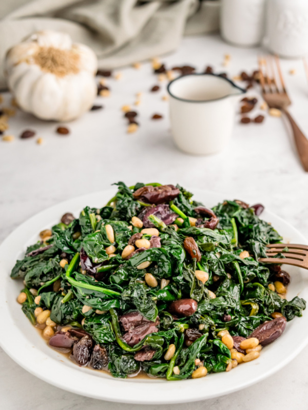 plate of spinach with olives raisins and pine nuts