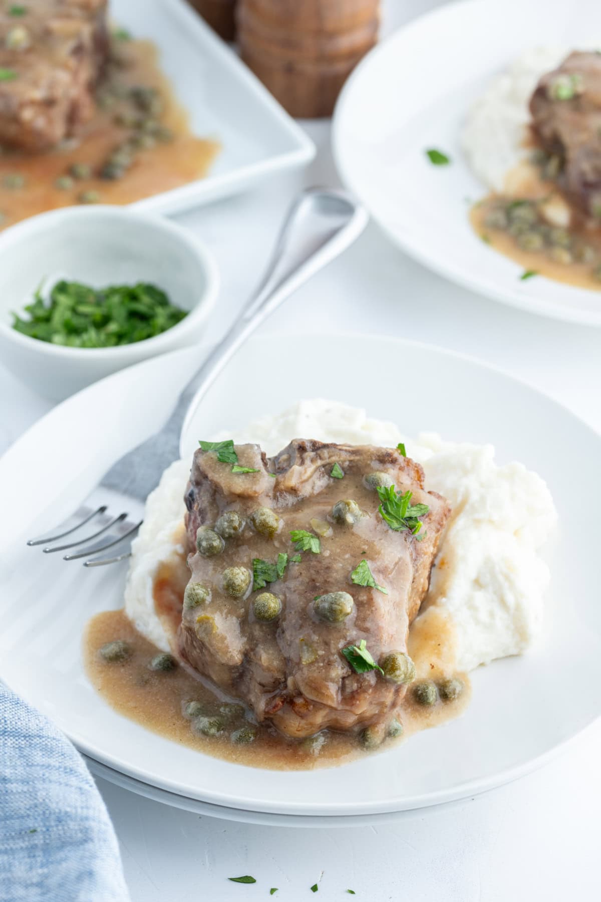 lamb chop over mashed potatoes with caper sauce on top