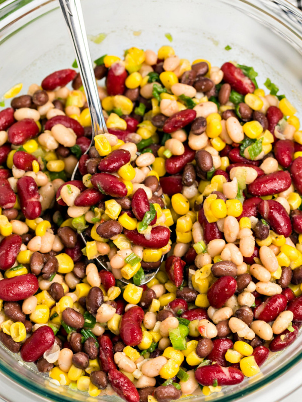 Red White and Black Bean Salad in a glass bowl with a spoon