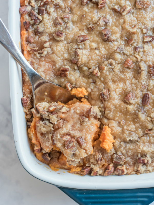 streuseled sweet potatoes in white dish with serving spoon taking some out